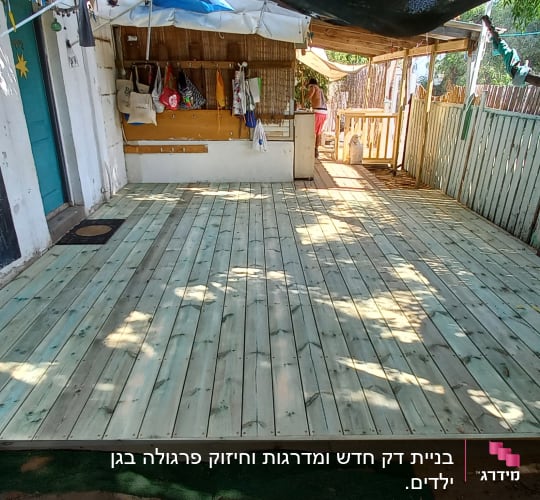 רצפת עץ חדשה בחצר עם גדר עץ מסביב